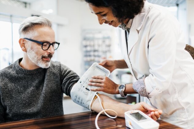 A doctor applying a blood pressure cuff to a man's arm.