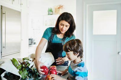 Mother and child unpacking groceries in the kitchen.