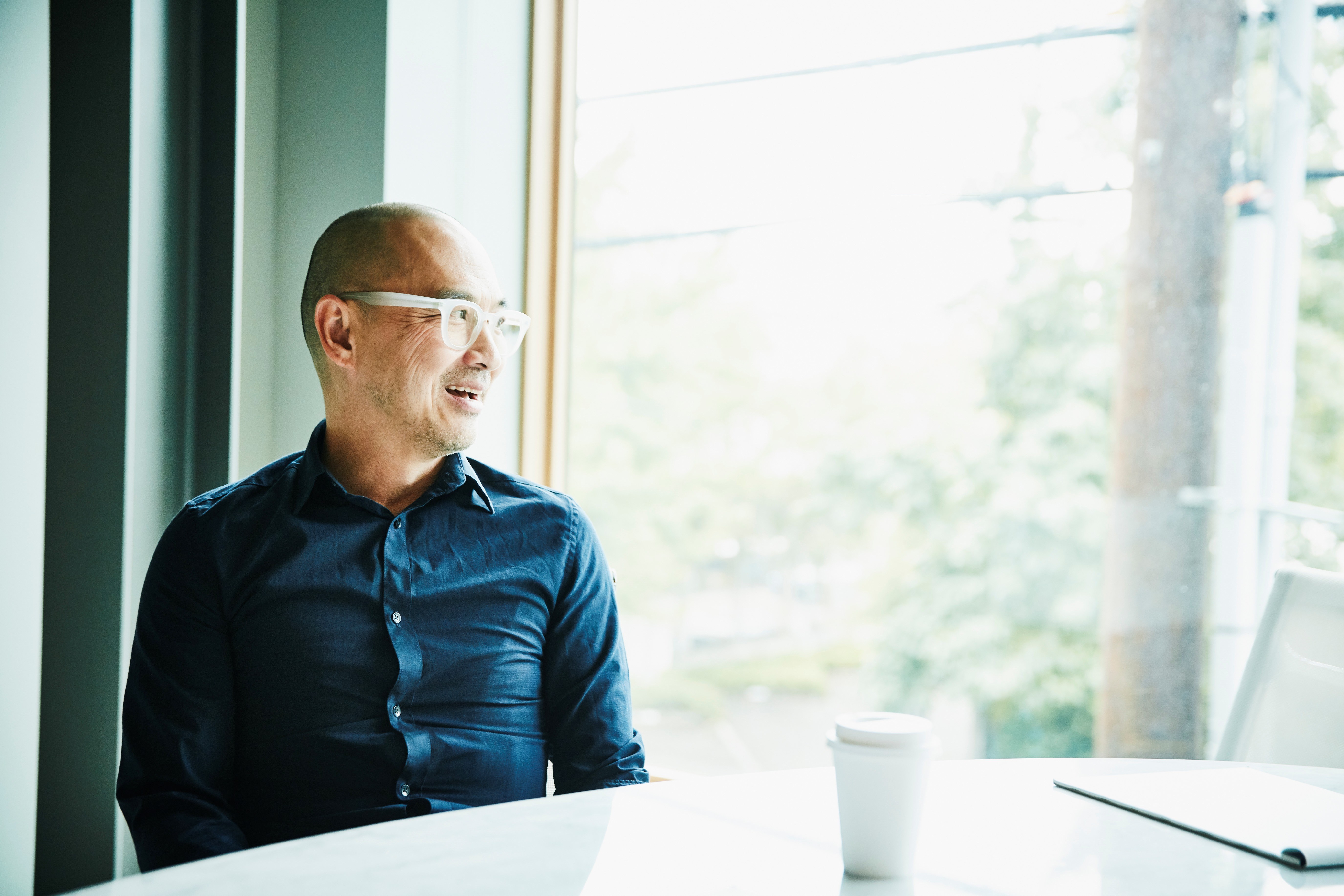 Man with glasses looking out a window.