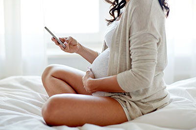 A pregnant woman looking at her phone.