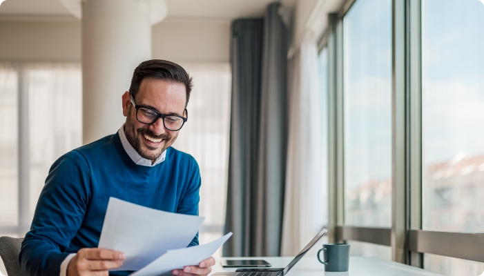 A man with glasses looking at documents on a desk.