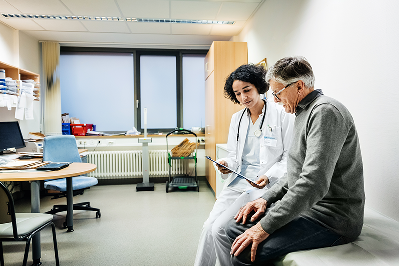 A doctor and patient looking at a clipboard together in a doctors office.