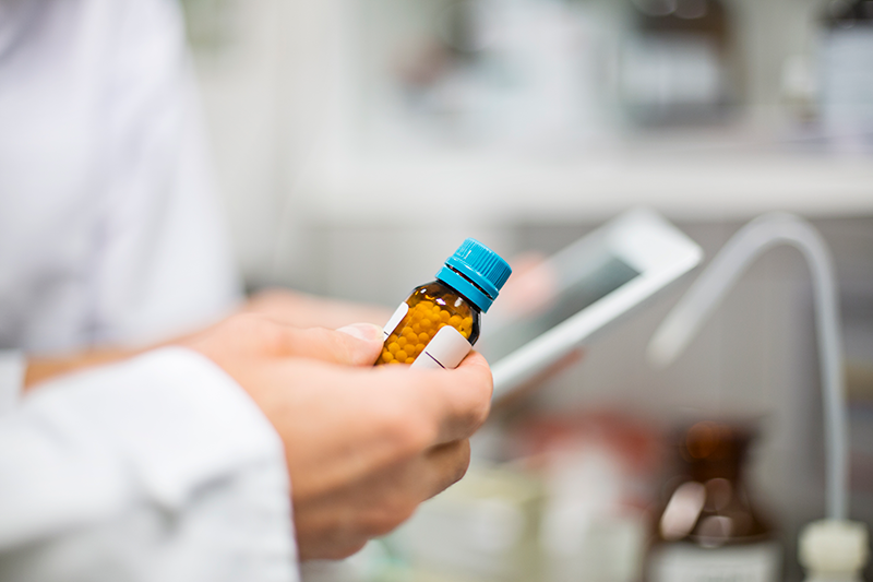 A close-up of a pharmacists' hands while they view a prescription label.